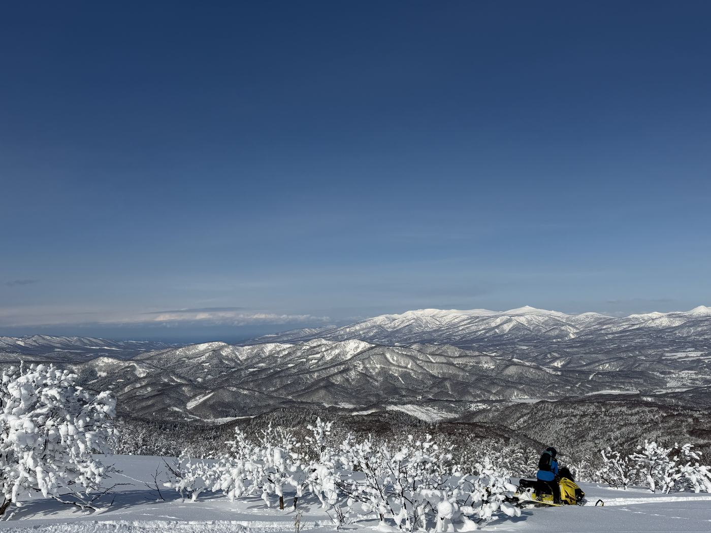 Vue depuis un sommet au Japon, motoneige et chaîne de montagnes enneigées